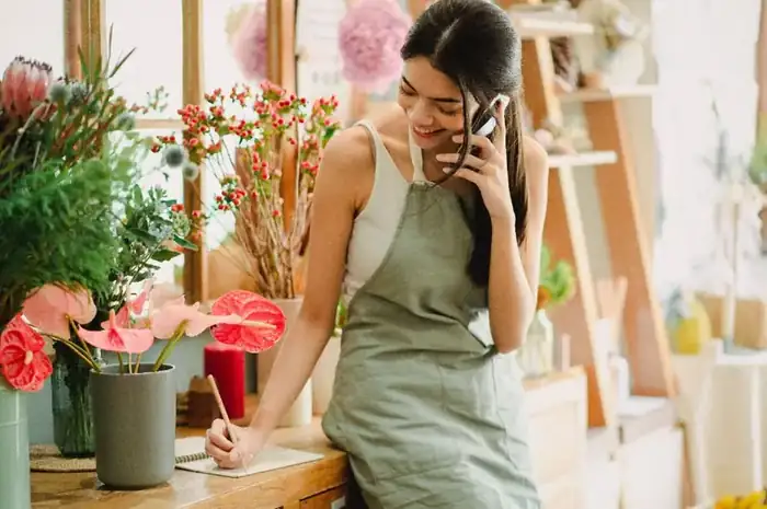 A local business owner on the phone, taking notes at the counter