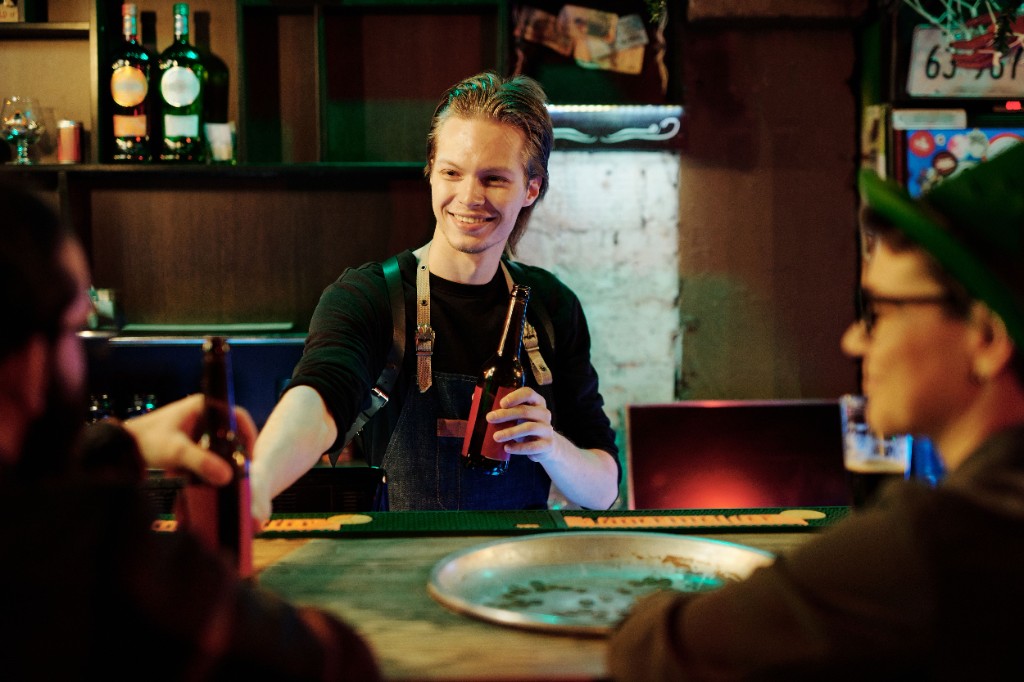 A bartender serving customers at a busy local bar